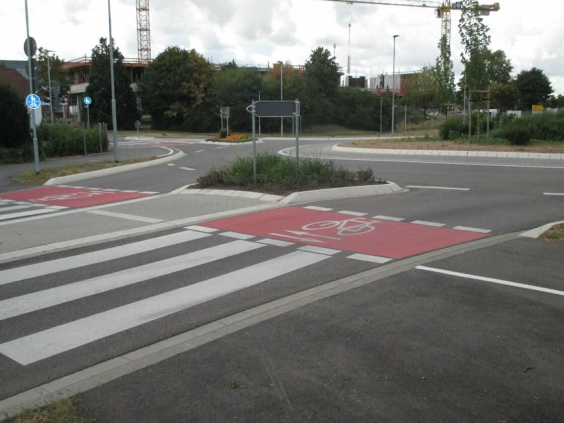 Zu sehen ist ein roter Radweg auf einer Kreuzung