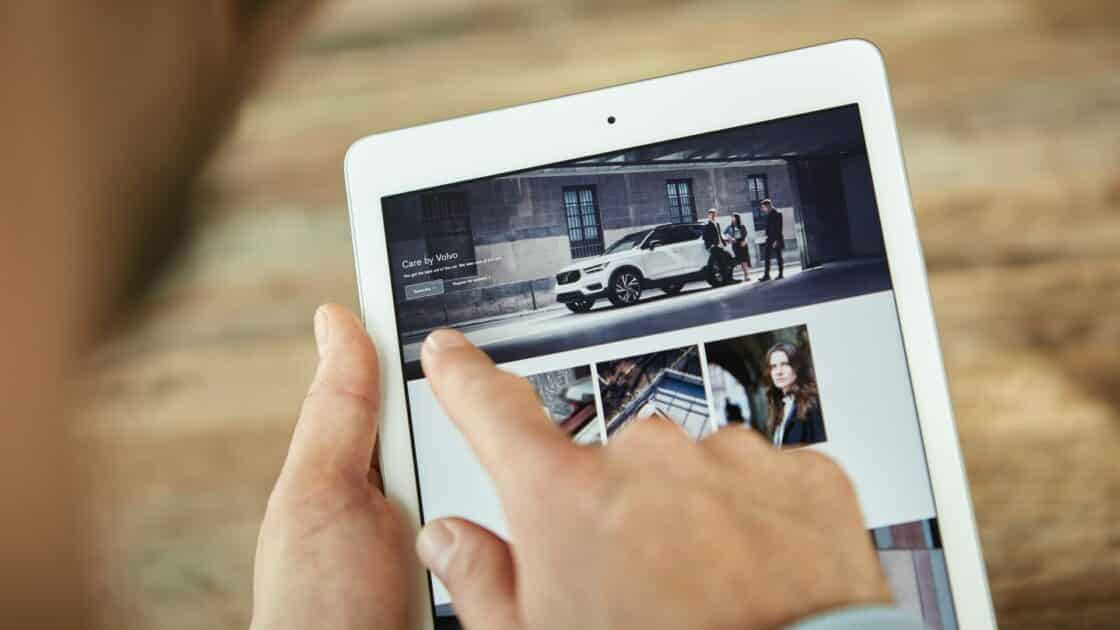 Ein Mann surft auf einem Tablet das Auto-Abo Care by Volvo an