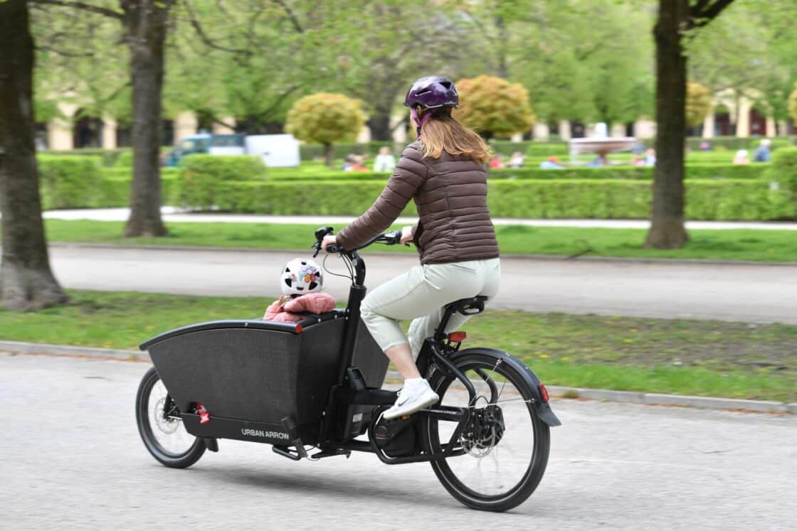 Frau auf einem Lastenrad mit Kind, fahrend