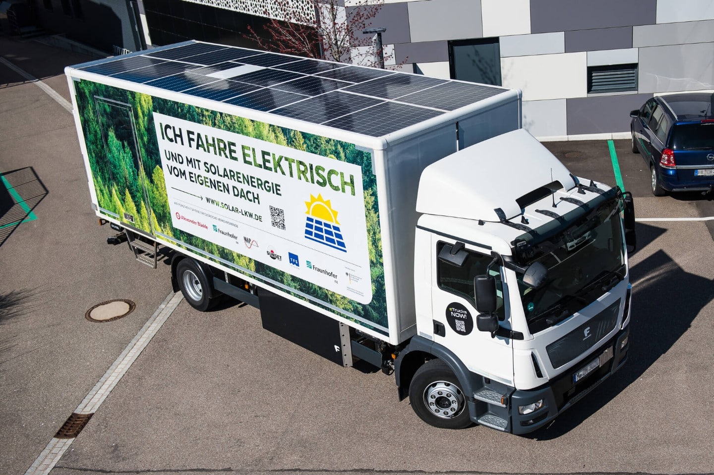 Ein Lastwagen mit Solar-Modulen auf dem Dach steht auf einem Unternehmens-Gelände
