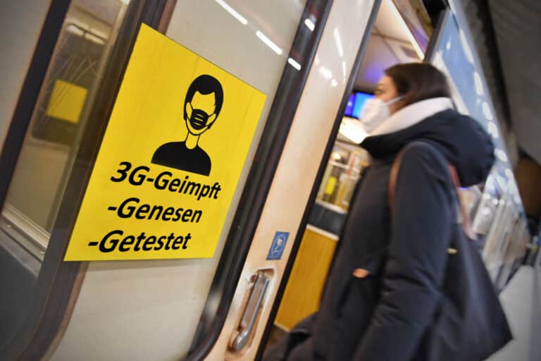 3G-Infosticker klebend an einer Berliner U-Bahn