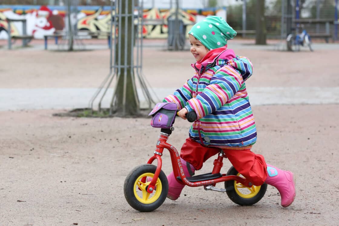 Zu sehen ist ein Kind auf einem Laufrad