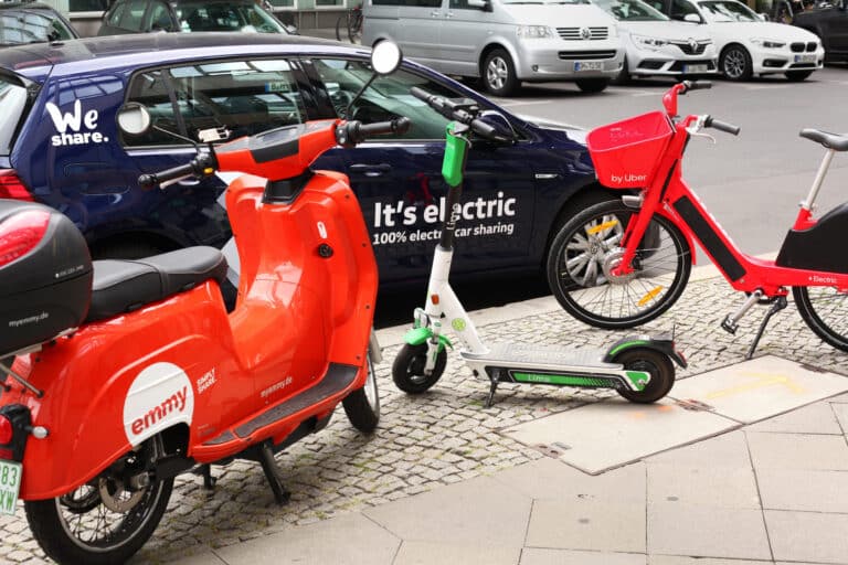 Zu sehen sind ein E-Roller, E-Scooter und E-Moped vor einem VW Sharing Auto