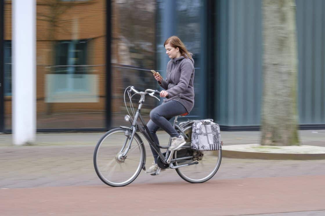 Eine Frau fährt auf einem Fahrrad und schaut auf ihr Smartphone