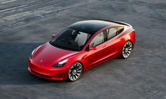 Ein rotes Tesla Model 3 steht auf einem Parkplatz
